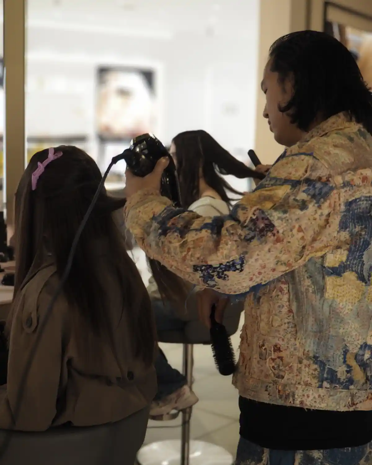 Hairdresser dries a client's hair with a hairdryer.