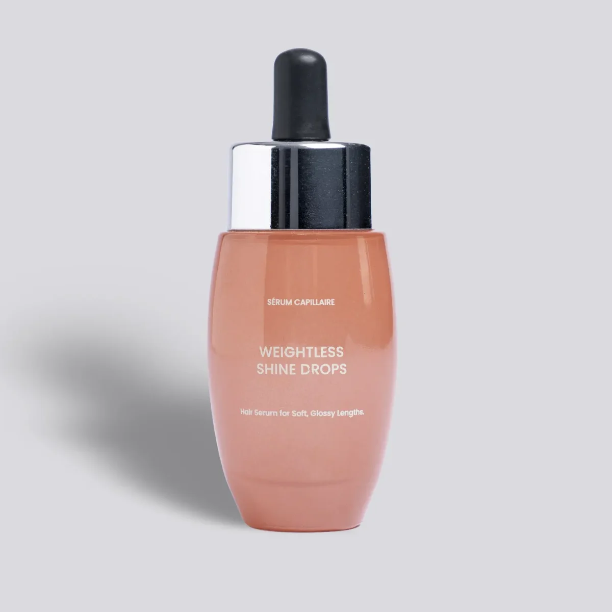 Glass bottle of Shine Drops peach liquid on a grey background.