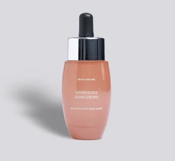 Glass bottle of Shine Drops peach liquid on a grey background.