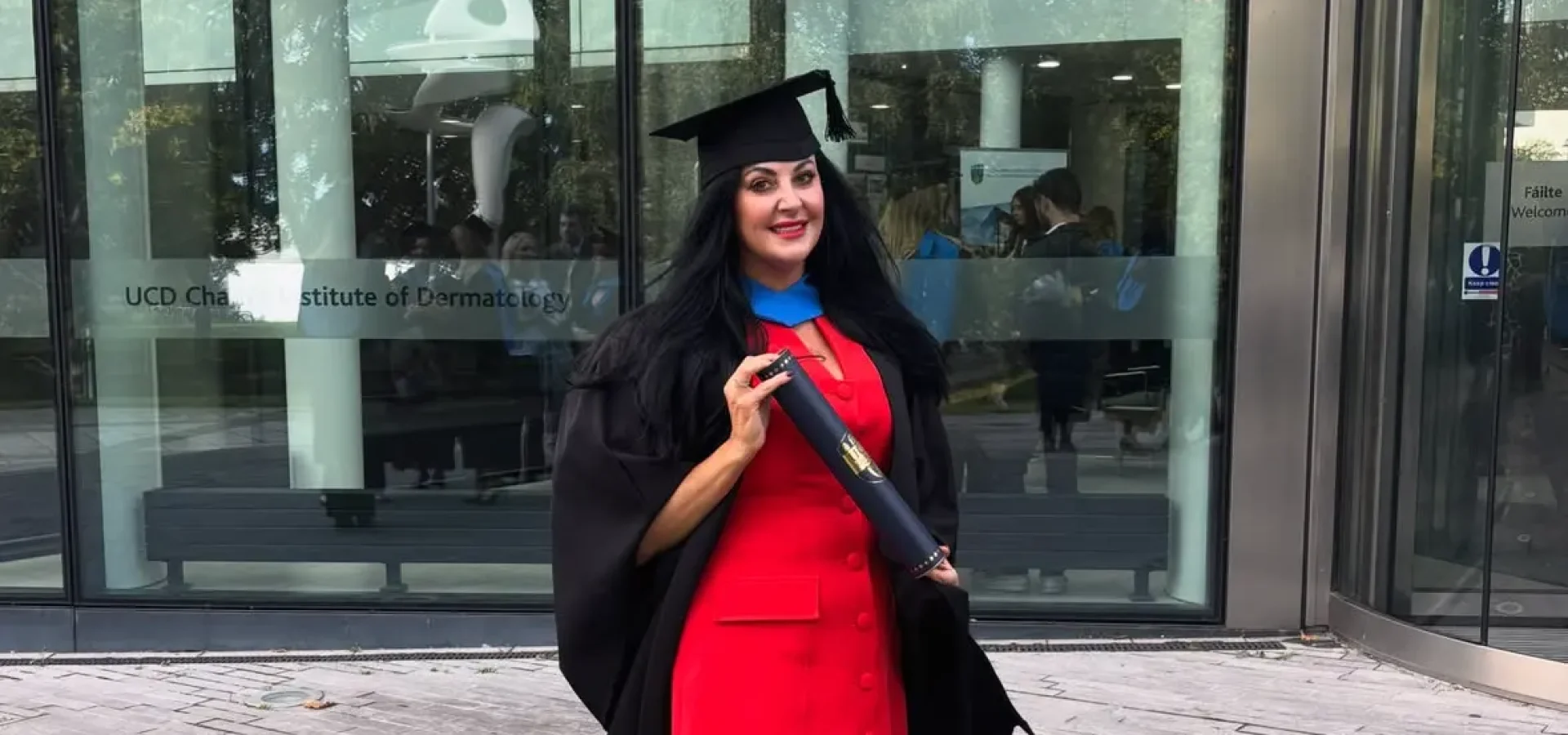 Bridgeen King stands outside a building wearing a graduation hat and holding a scroll.