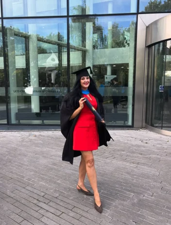 Bridgeen King stands outside a building wearing a graduation hat and holding a scroll.
