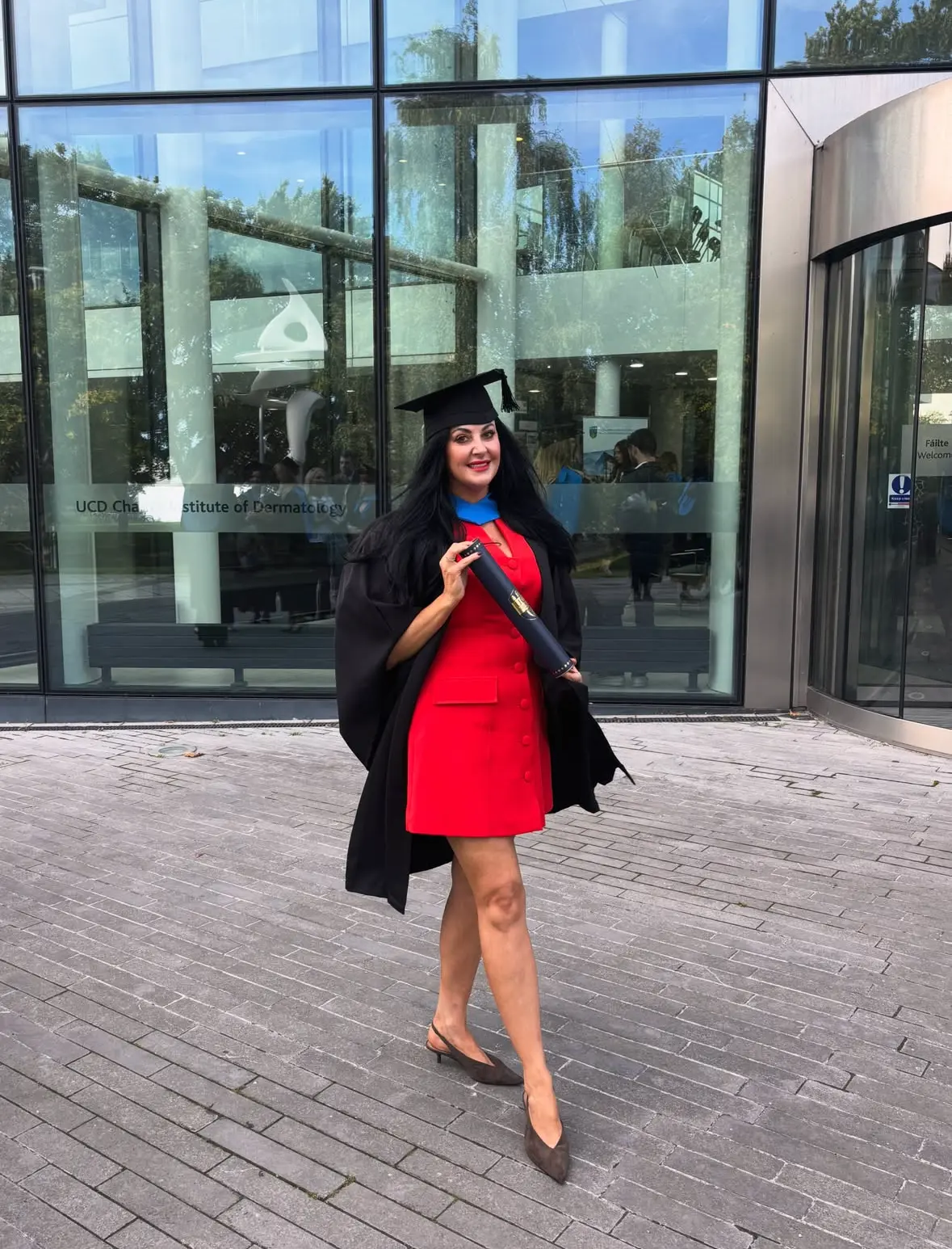 Bridgeen King stands outside a building wearing a graduation hat and holding a scroll.