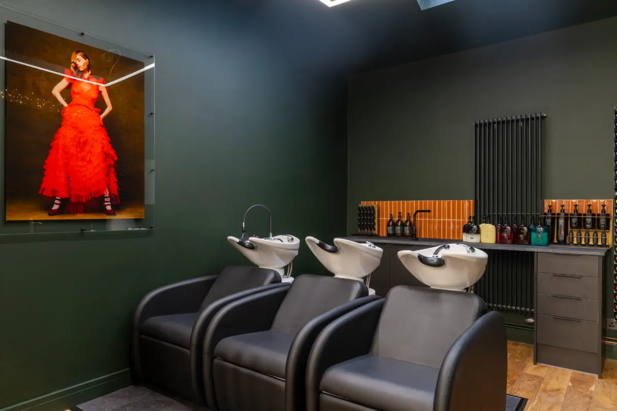 Backwashes inside KIKU Salon with a photo of a lady in a red dress on the wall.