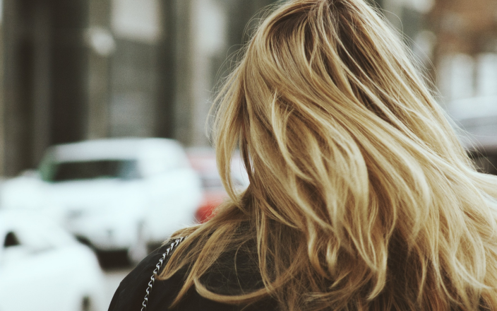 Model facing away from the camera with long blonde hair.