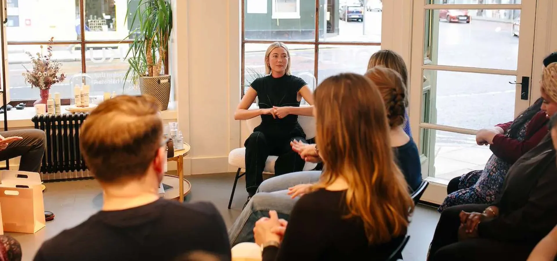 woman sits at the centre of a circle giving a talk.
