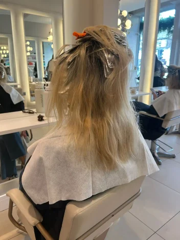 Client sits in a salon with foils in her blonde hair.