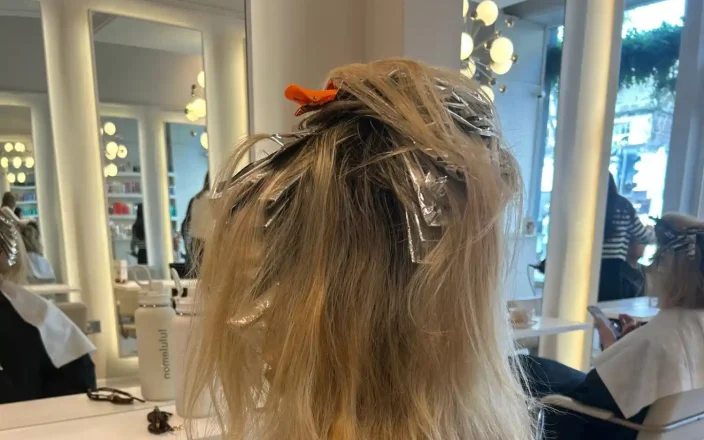 Client sits in a salon with foils in her blonde hair.