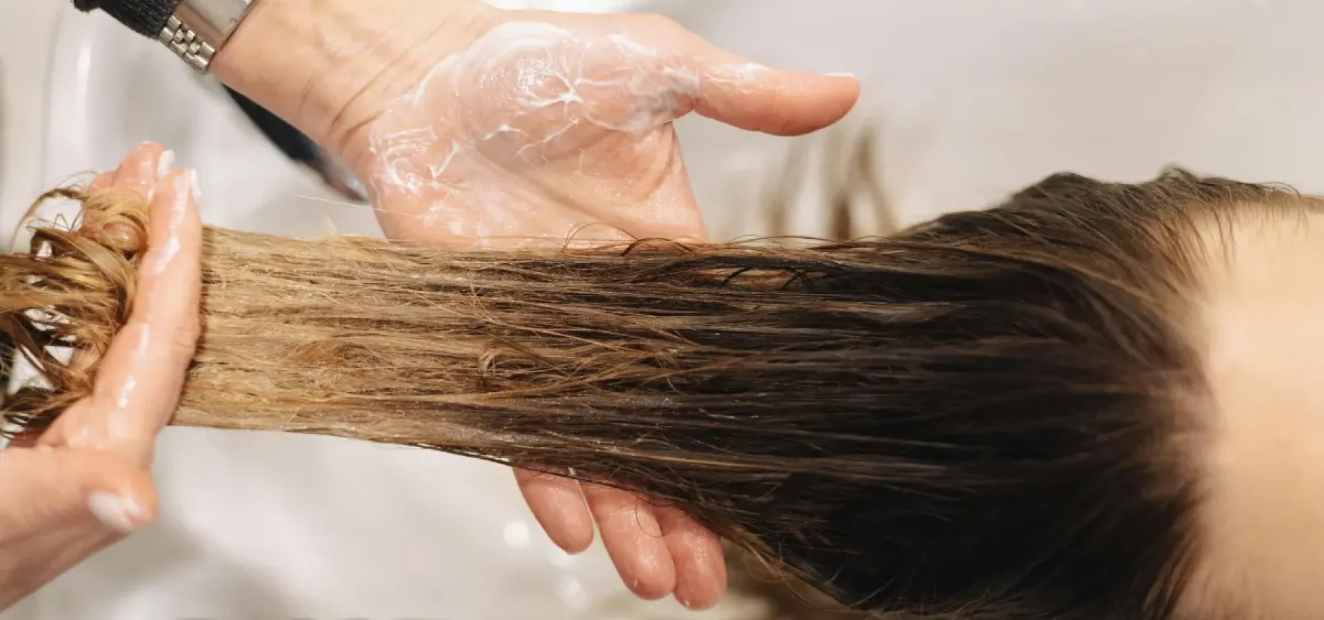 a hand washes long hair at a salon basin.