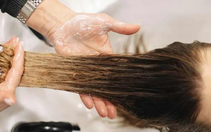 a hand washes long hair at a salon basin.